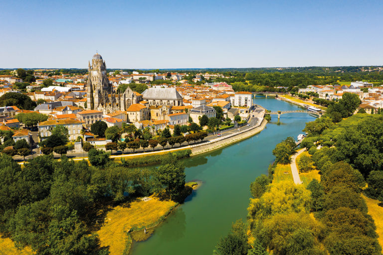 Picturesque summer view of historic areas of Saintes located on Charente river looking out over cathedral bell tower in Flamboyant Gothic style, Charente-Maritime, France..